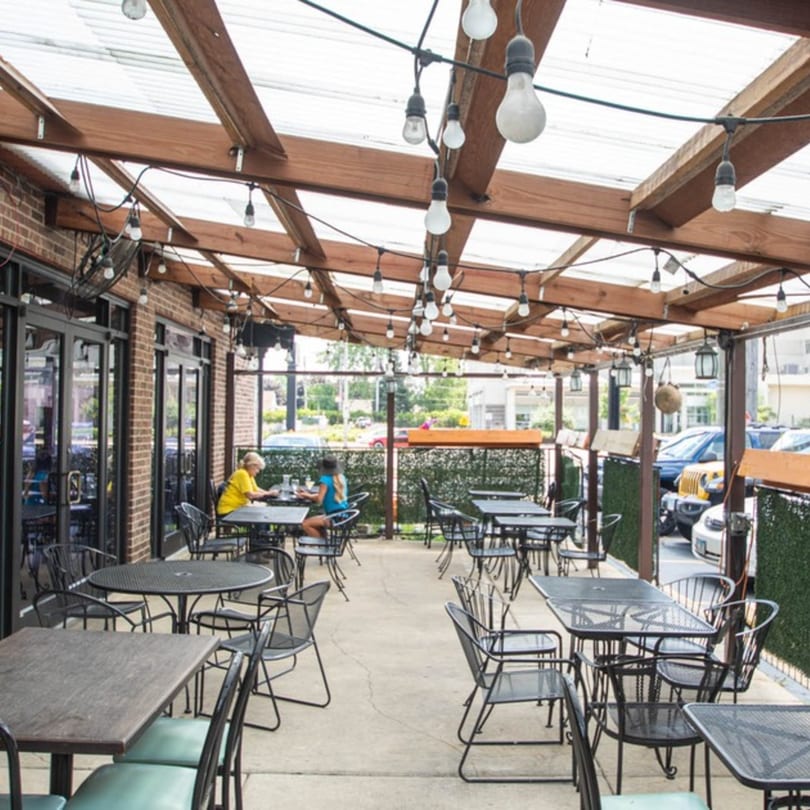 Alejandra's Mexican Restaurant outdoor patio with string lights, brick wall, and two people dining.