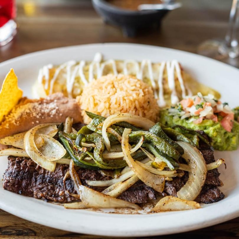 Alejandra's Mexican Restaurant's carne asada with grilled onions, peppers, rice, beans, guacamole, and an enchilada.