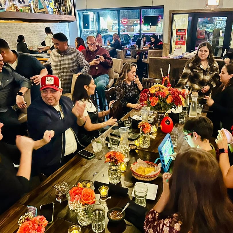 Diners enjoying a lively evening at Alejandra's Mexican Restaurant, with colorful floral centerpieces on tables.