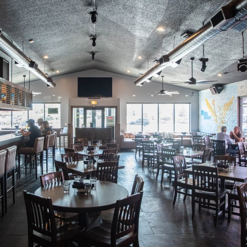 Spacious Alejandra's Mexican Restaurant dining room with tables, bar seating, and a winged mural.