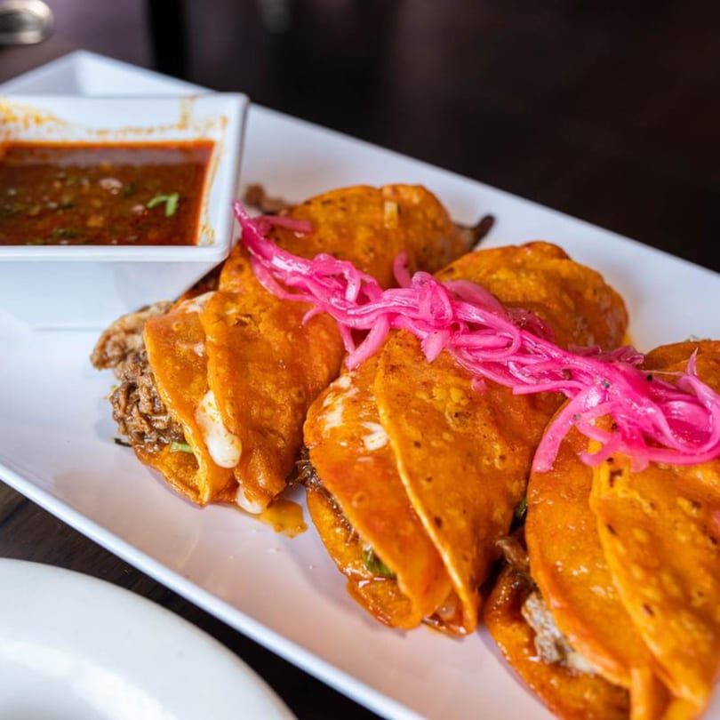 Alejandra's Mexican Restaurant birria tacos with pickled red onions and a side of consommé.